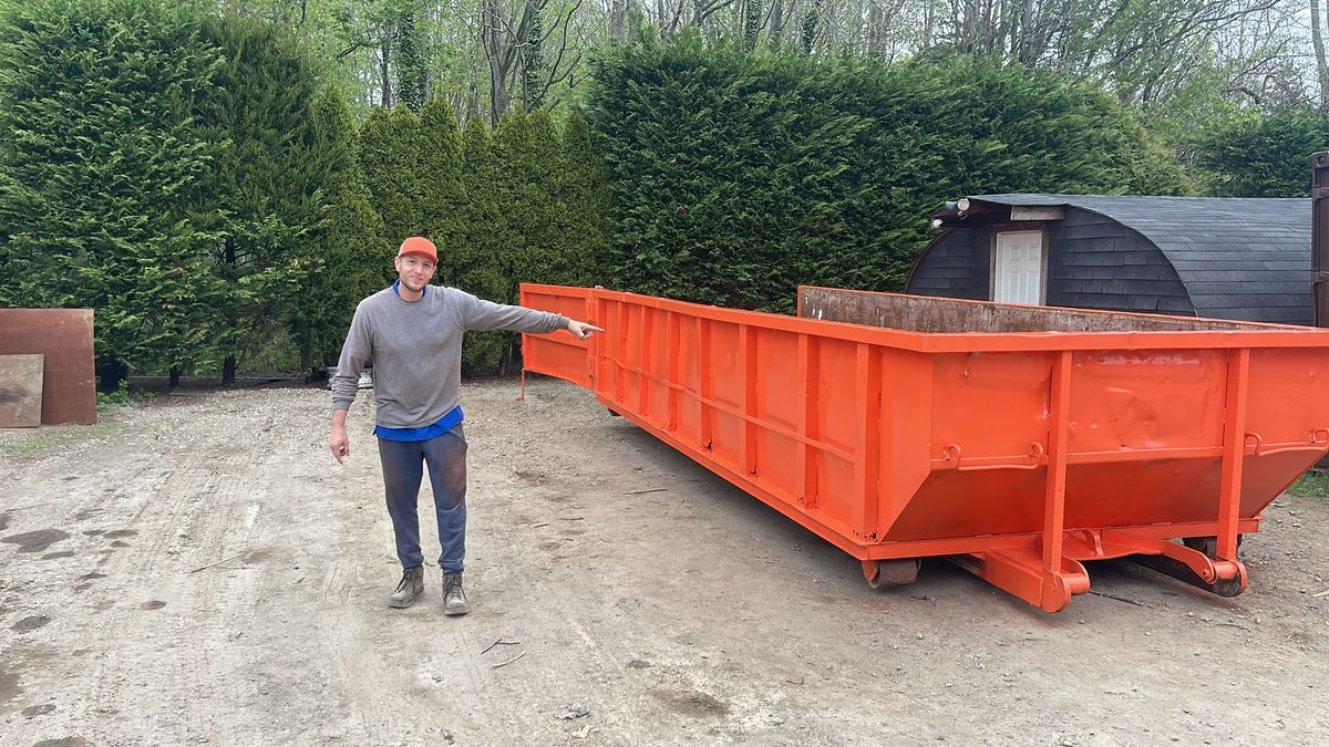 The Hamptons Pick Up owner beside one of the company's roll-off containers